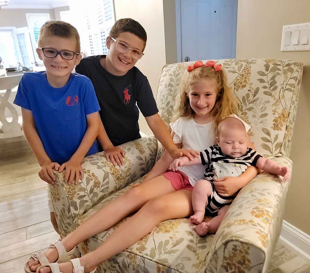 Two boys and a little girl with a baby.