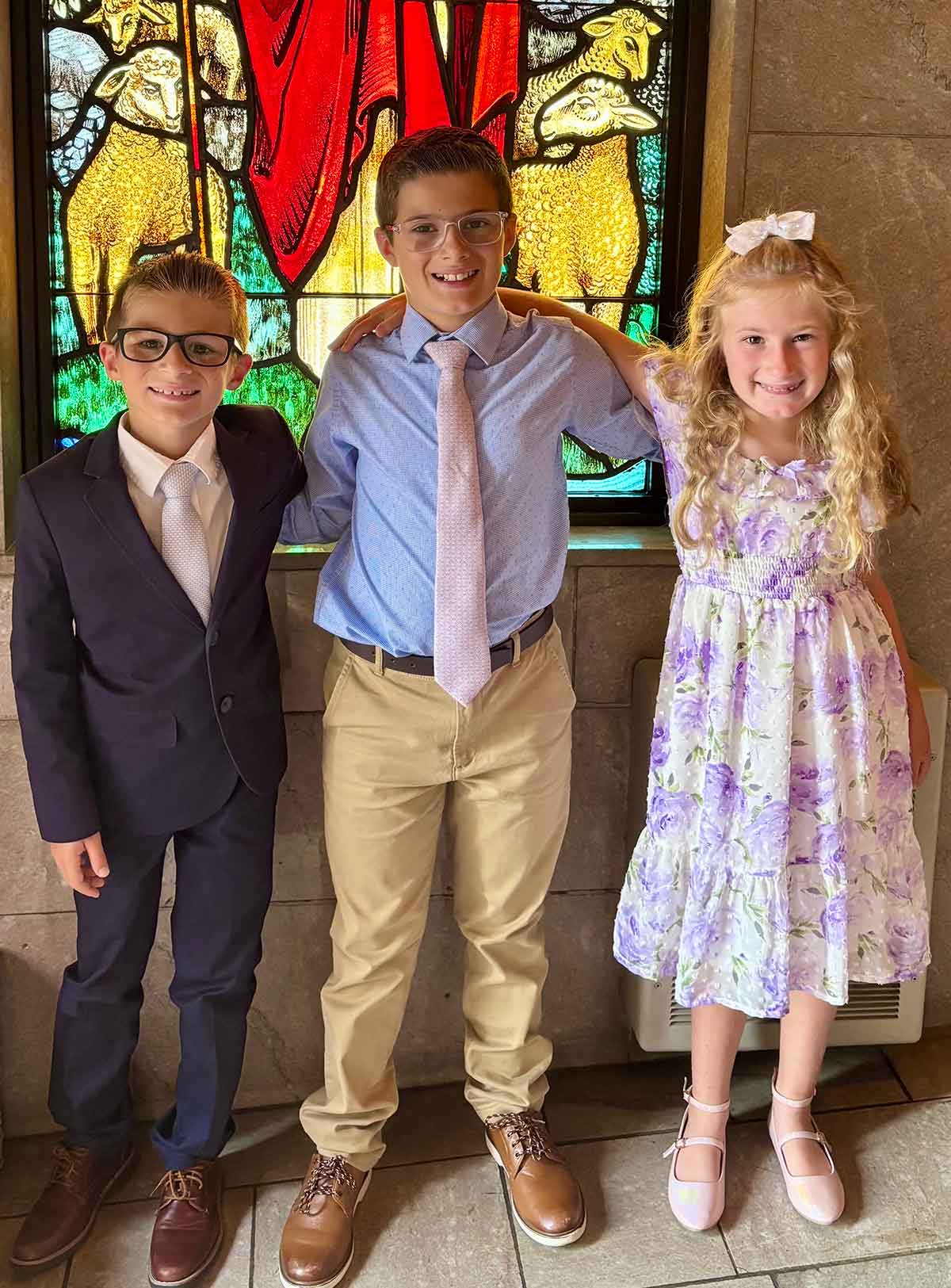 Two boys and a girl in dress clothes at a church.