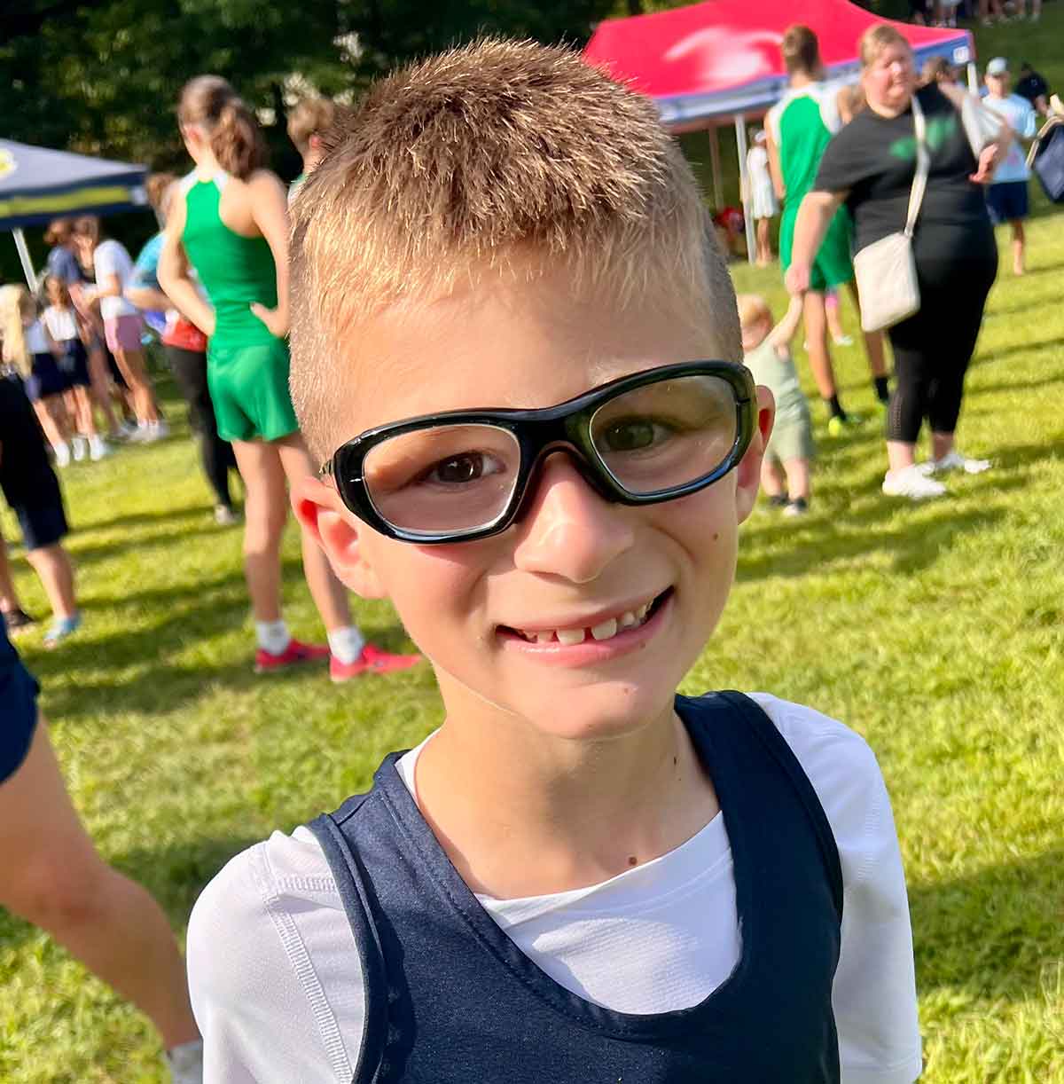 Boy in black sports glasses on a field.